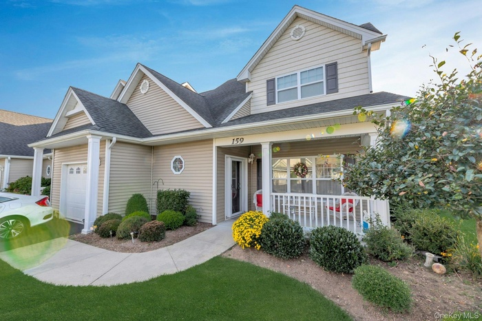 View of front of home featuring roof with shingles, covered porch, and a garage