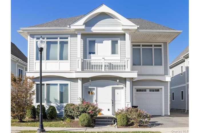 View of front of property featuring a balcony, roof with shingles, and a garage