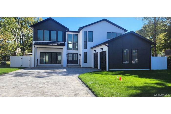 Contemporary house with decorative driveway, stucco siding, a garage, and a gate