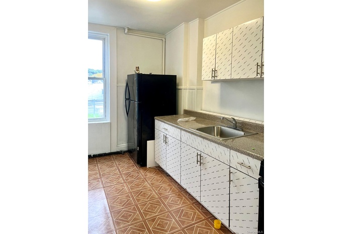 Kitchen with wainscoting, white cabinets, freestanding refrigerator, and dark countertops