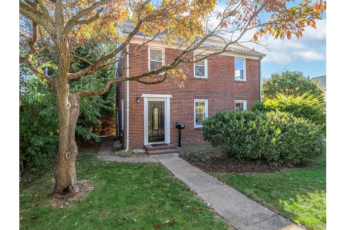 Colonial house with a front lawn and brick siding