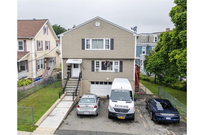View of front facade with a garage, stairs, and uncovered parking