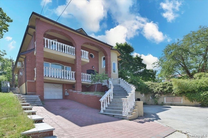 View of front of home featuring a balcony, stairs, decorative driveway, and a garage