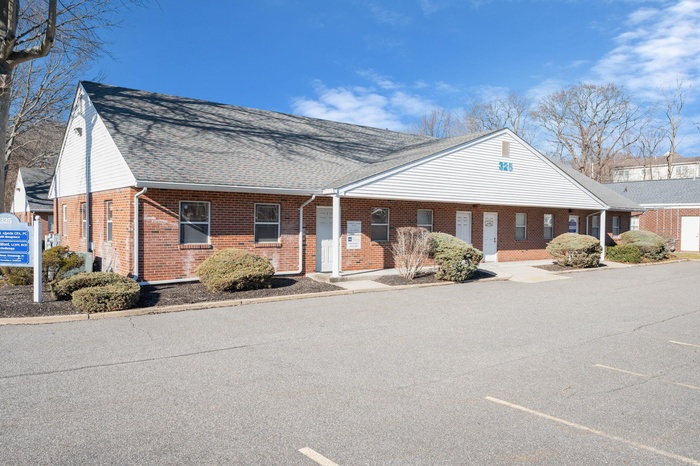 View of front of house featuring brick siding and roof with shingles