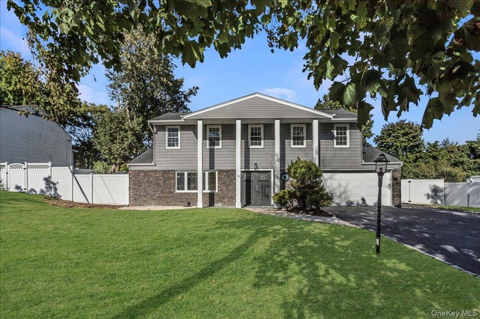 Greek revival house with asphalt driveway, stone siding, and a garage