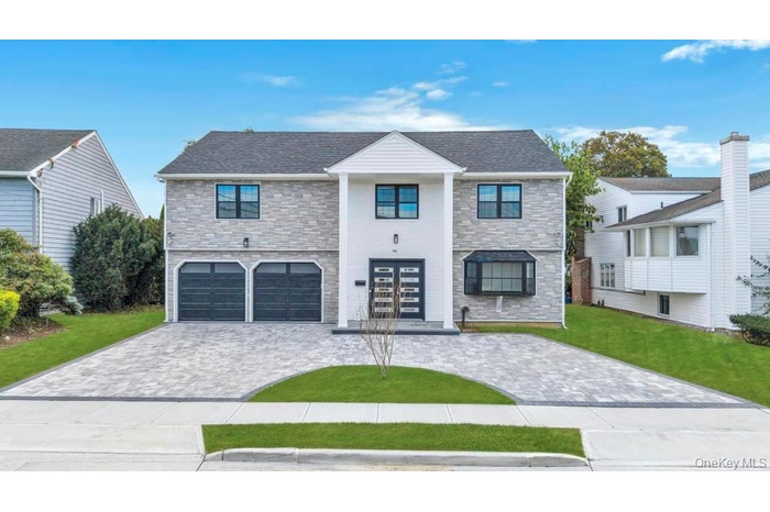 View of front of house featuring decorative driveway, a front lawn, and a garage