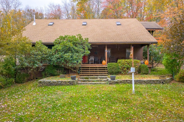 View of front of house featuring roof with shingles, a front lawn, and a porch