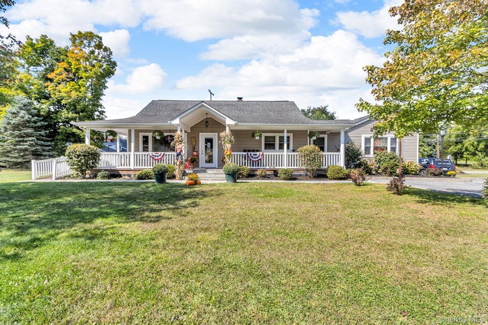 View of front of property featuring a porch, a front yard, and roof with shingles