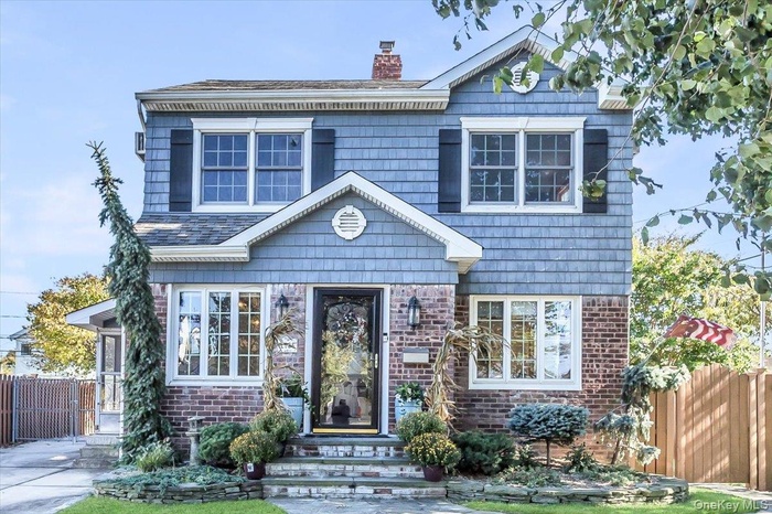 View of front of house featuring a chimney and brick siding