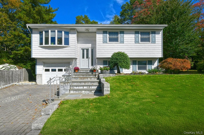 Bi-level home with decorative driveway and a garage