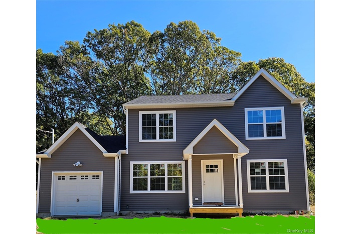 Traditional-style home featuring a garage and a front lawn