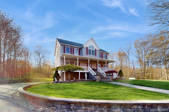 View of front of house with covered porch, stairway, and a front lawn