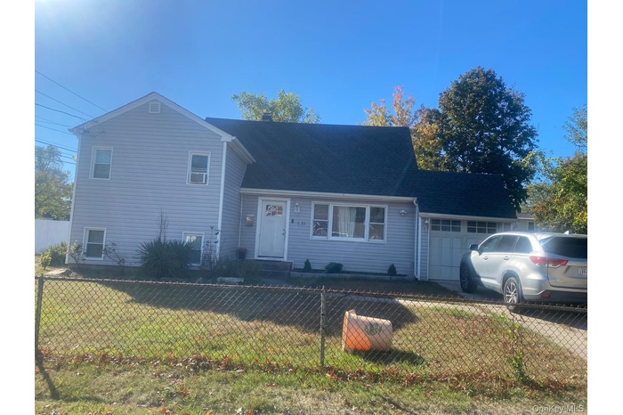 Split level home featuring a fenced front yard, a garage, and a shingled roof