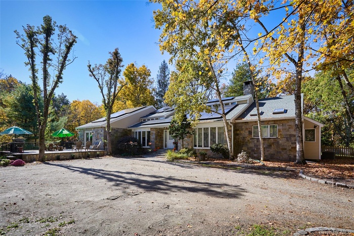 Mid-century home with stone siding, solar panels, and a chimney