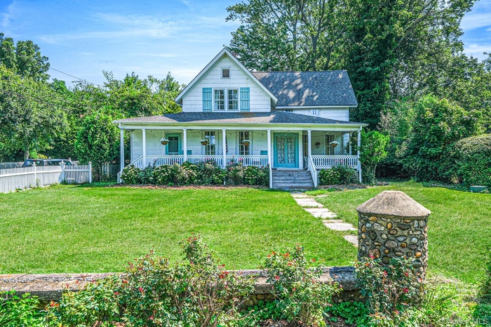 Farmhouse inspired home with a shingled roof and a porch