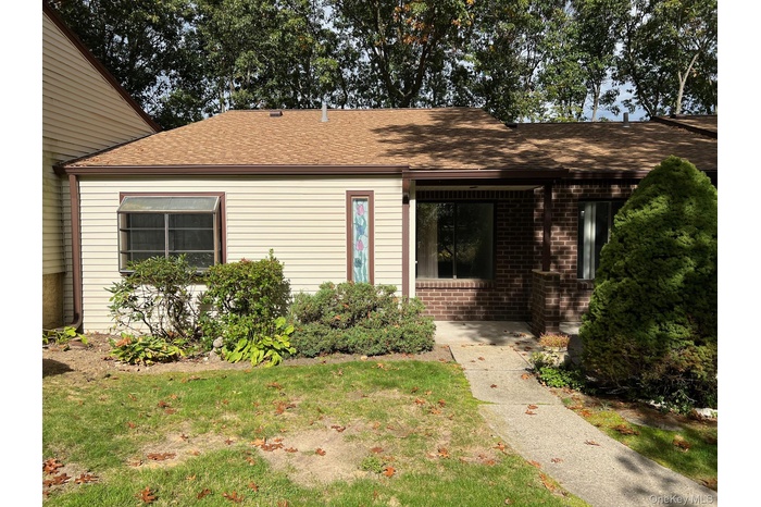 View of front facade featuring a front yard, brick siding, and roof with shingles