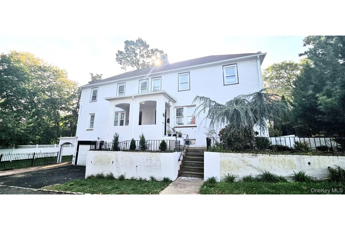 View of front facade featuring a fenced front yard, an attached garage, stairs, driveway, and stucco siding
