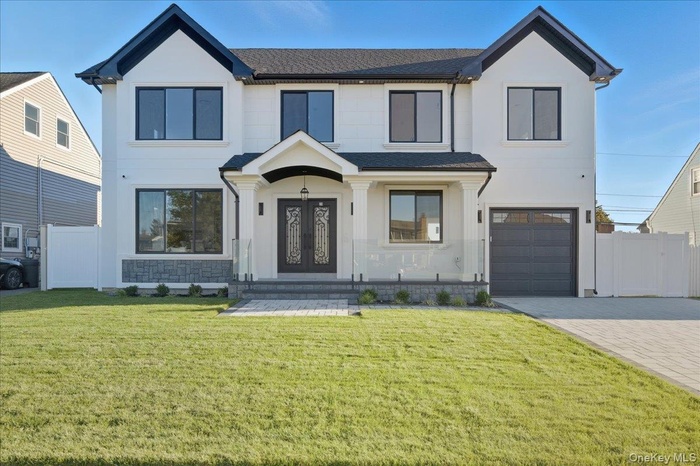 View of front facade with roof with shingles, decorative driveway, stucco siding, and a garage
