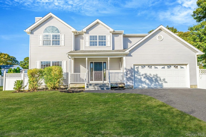 Traditional-style home with covered porch, driveway, and a garage