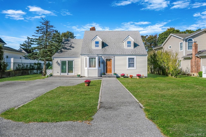Cape cod house with a chimney, roof with shingles, and asphalt driveway