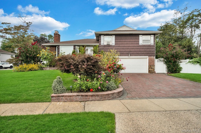 Tri-level home with decorative driveway, a garage, and a chimney