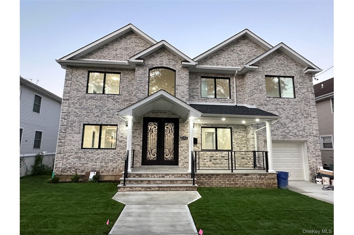 View of front of home with a front yard, brick siding, a garage, and covered porch
