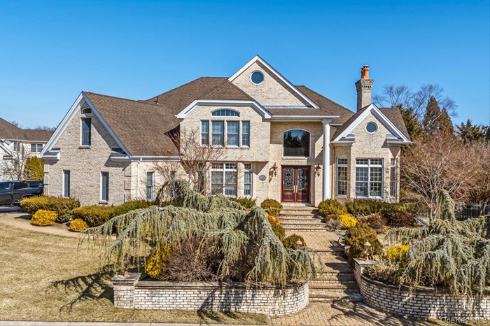 Traditional-style home featuring brick siding, french doors, a chimney, and roof with shingles