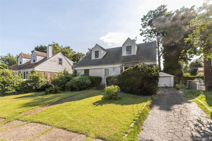 Cape cod-style house featuring a detached garage and an outbuilding