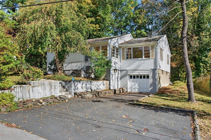 View of front of home featuring asphalt driveway, a garage, and view of wooded area