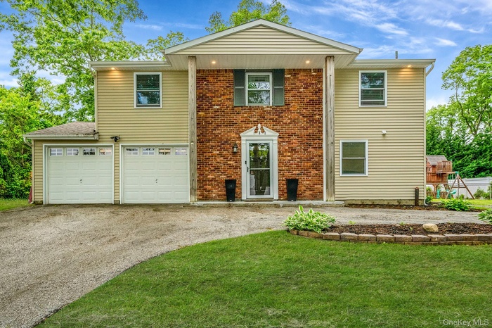 View of front of house featuring a front lawn, driveway, a garage, and brick siding