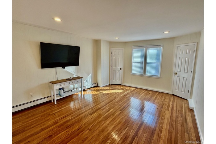 Unfurnished living room featuring light wood-style floors, recessed lighting, and baseboard heating