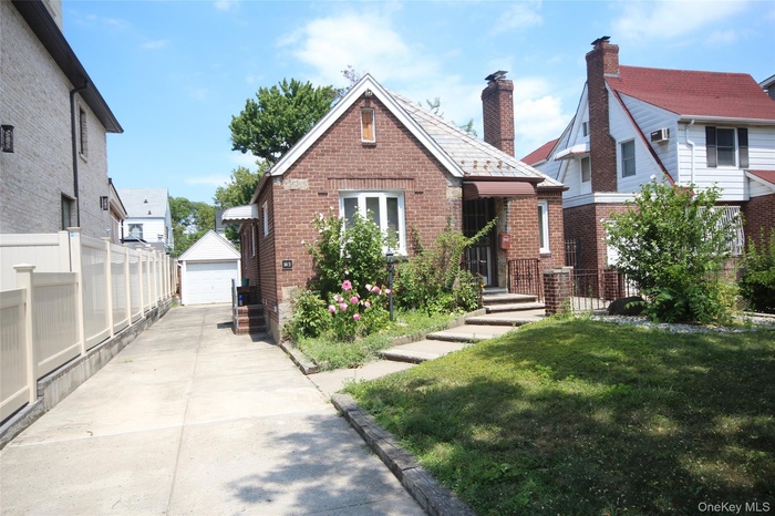 View of front of house with an outbuilding, brick siding, and a detached garage