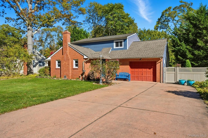 Traditional-style home with a garage, brick siding, concrete driveway, roof with shingles, and a chimney