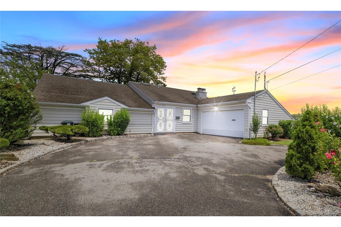 Ranch-style home with driveway, an attached garage, french doors, a shingled roof, and a chimney