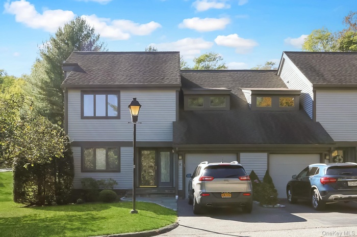 View of front of property featuring concrete driveway, a garage, roof with shingles, and a front yard