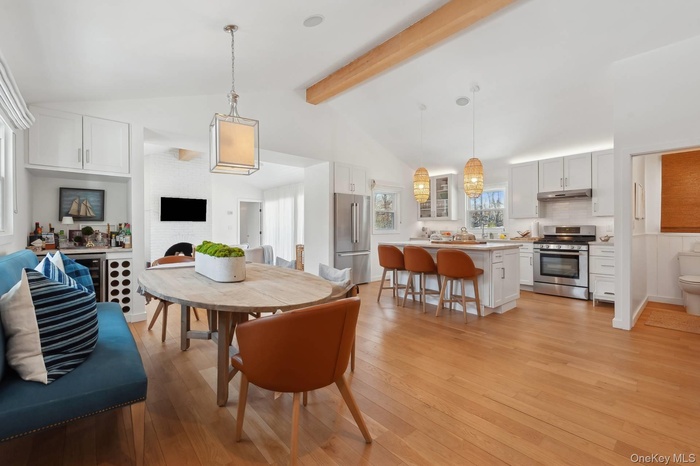 Dining room featuring high vaulted ceiling, light wood finished floors, a fireplace, and beam ceiling