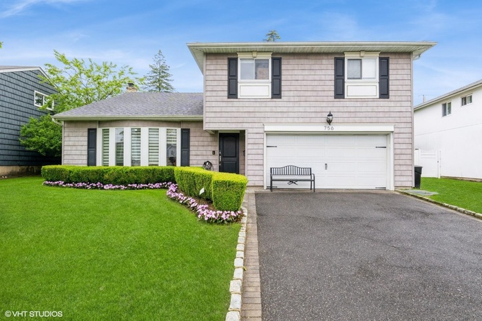 View of front of house with a garage, driveway, a front lawn, and a chimney
