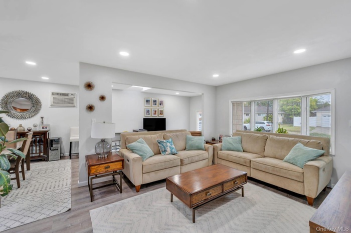 Living area featuring recessed lighting, light wood-style flooring, and a wall mounted air conditioner