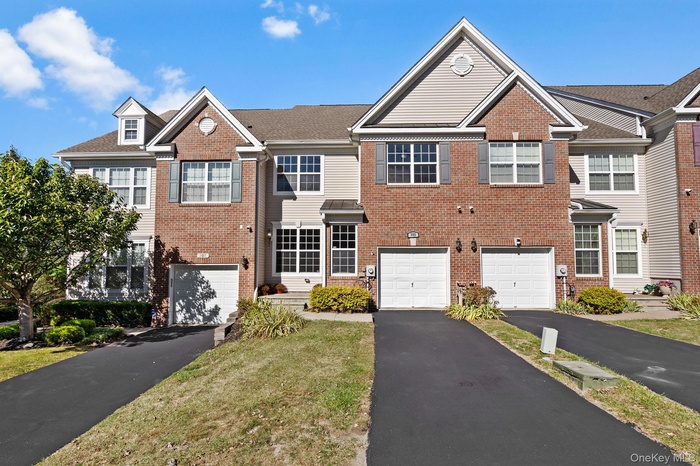 Traditional-style home with brick siding, driveway, and a front lawn