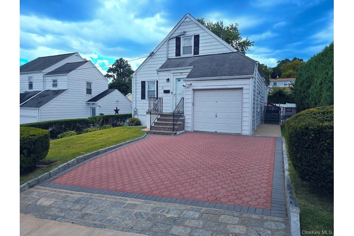 View of front of house featuring decorative driveway, a garage, a front yard, and a shingled roof