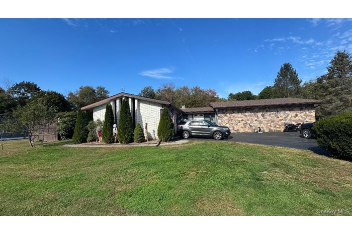 View of side of home with a lawn and stone siding