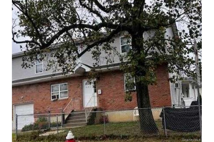 View of front of house featuring a fenced front yard, an attached garage, and brick siding