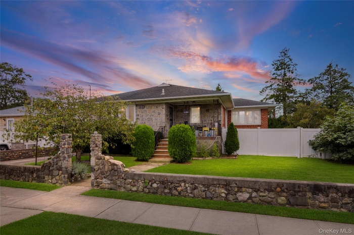 View of front of property with brick siding, roof with shingles, and covered porch