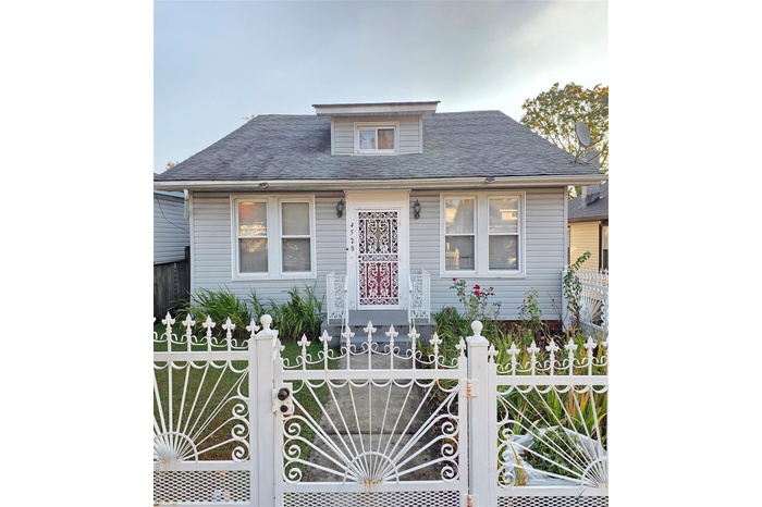 Bungalow with a shingled roof and a fenced front yard