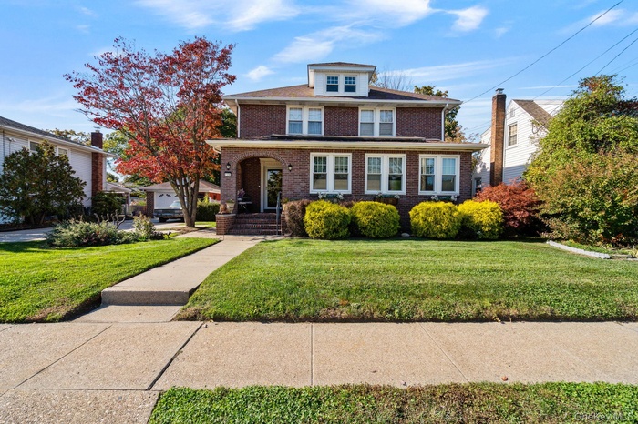 American foursquare style home featuring brick siding and a front yard