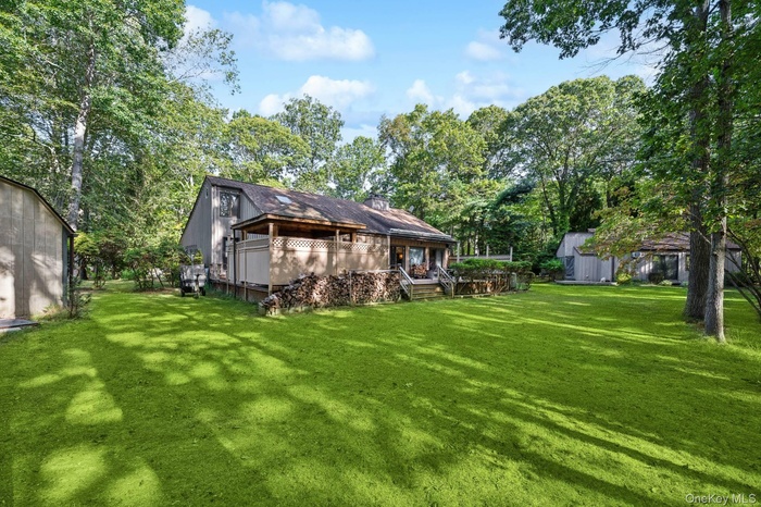 View of green lawn with view of wooded area and a storage unit