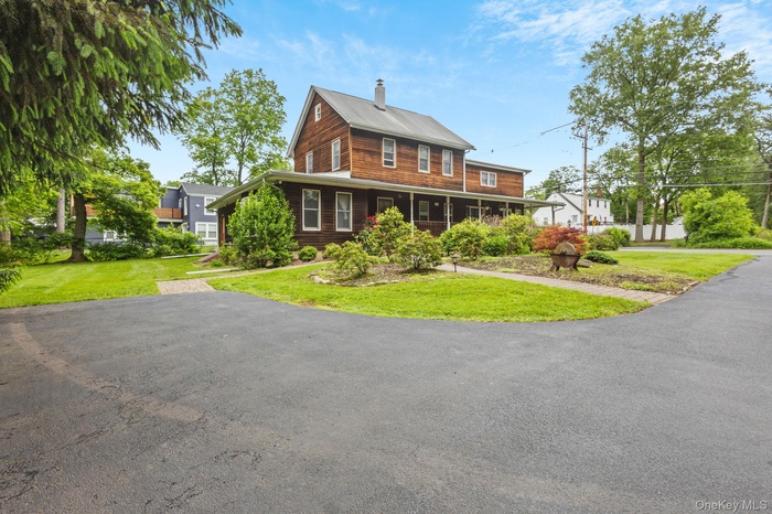 View of front of property featuring a chimney, a front yard, and covered porch