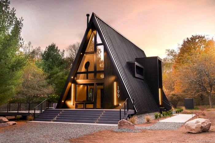 A-frame style home featuring view of scattered trees and stairway