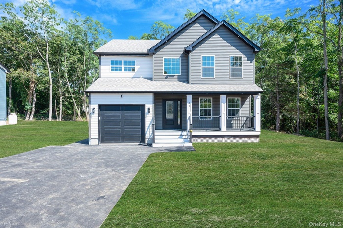 View of front of property featuring a porch, driveway, a shingled roof, a front yard, and an attached garage