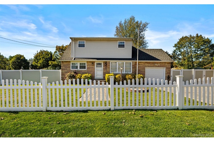 View of front of home with a garage, a fenced front yard, and roof with shingles